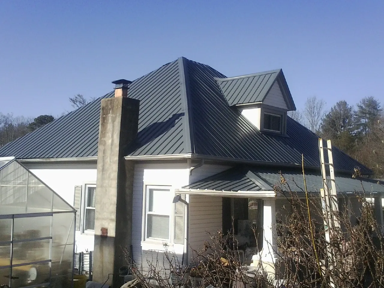Dark blue standing seam metal roof on a white farmhouse with dormer — Slate & Tile Roof Repair by Roofing Brothers in North Dartmouth