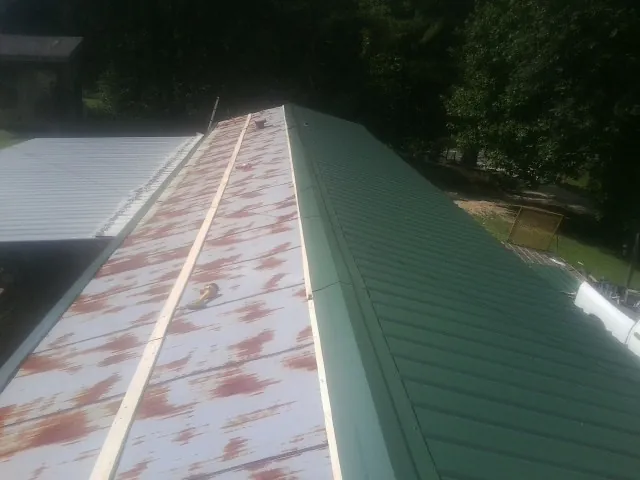 Old rusted panels beside newly installed green metal roofing — Wind Damage Roof Repair by Roofing Brothers in North Dartmouth