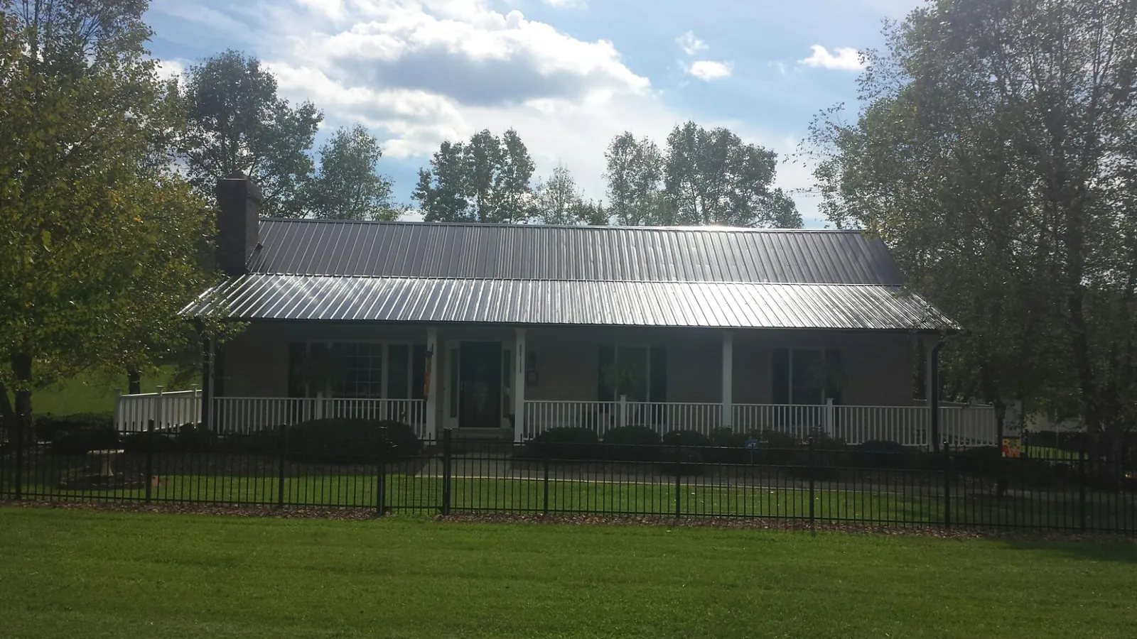 Gray metal roof on a brick ranch with a full width front porch — Gutter Guard Installation work by our crew in North Dartmouth