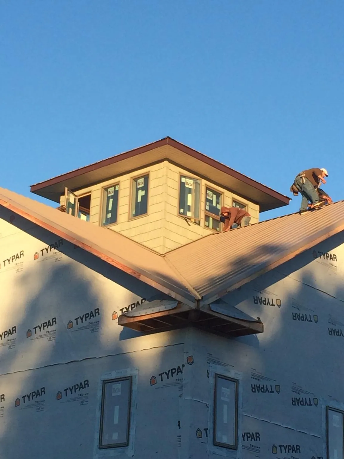 Roofers working around a rooftop cupola on a new metal roof at sunset — Roof Waterproofing in North Dartmouth by Roofing Brothers